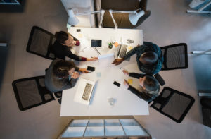 Office workers gather around a table to do research and implement new ideas. High angle view of multi-ethnic business people discussing in board room meeting