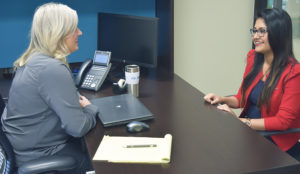 Two women in an office smiling and discussing student health care solutions