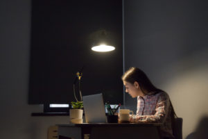 A woman sitting alone at in a small room with her laptop open to study