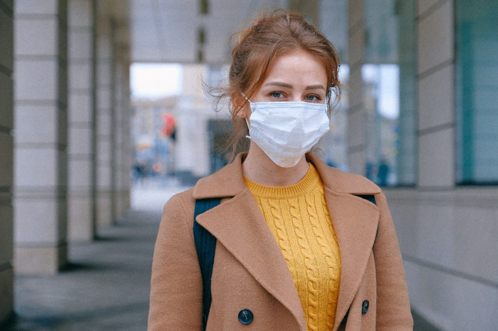 young woman in a mask walks the streets wearing her backpack