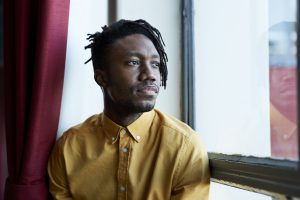 Thoughtful young man looking away through window in university cafeteria