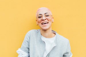 Portrait of happy young woman with short pink hair, wearing glasses