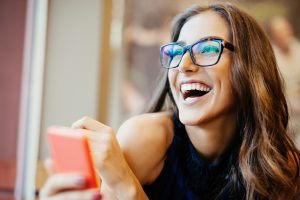 Young woman wearing glasses with smart phone indoors