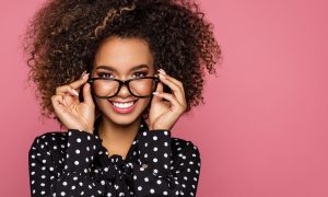 Beauty portrait of a young black healthy woman holding glasses and looking at camera