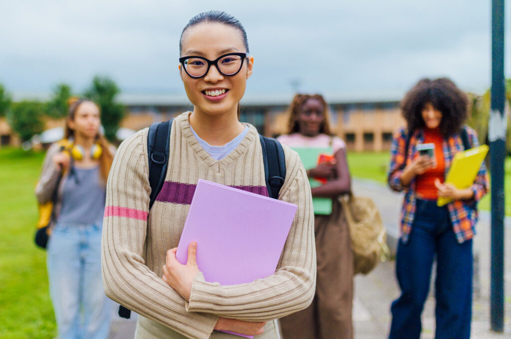 International University student smiling and holding book on campus