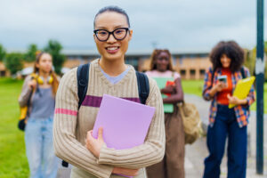 International University student smiling and holding book on campus